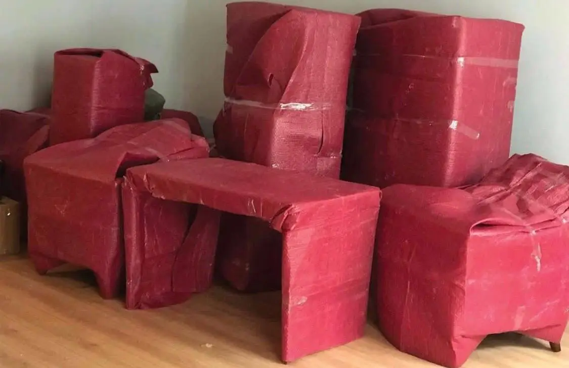 Göktürk nakliyat: kırmızı koruyucuyla paketlenmiş masa ve koltuklar